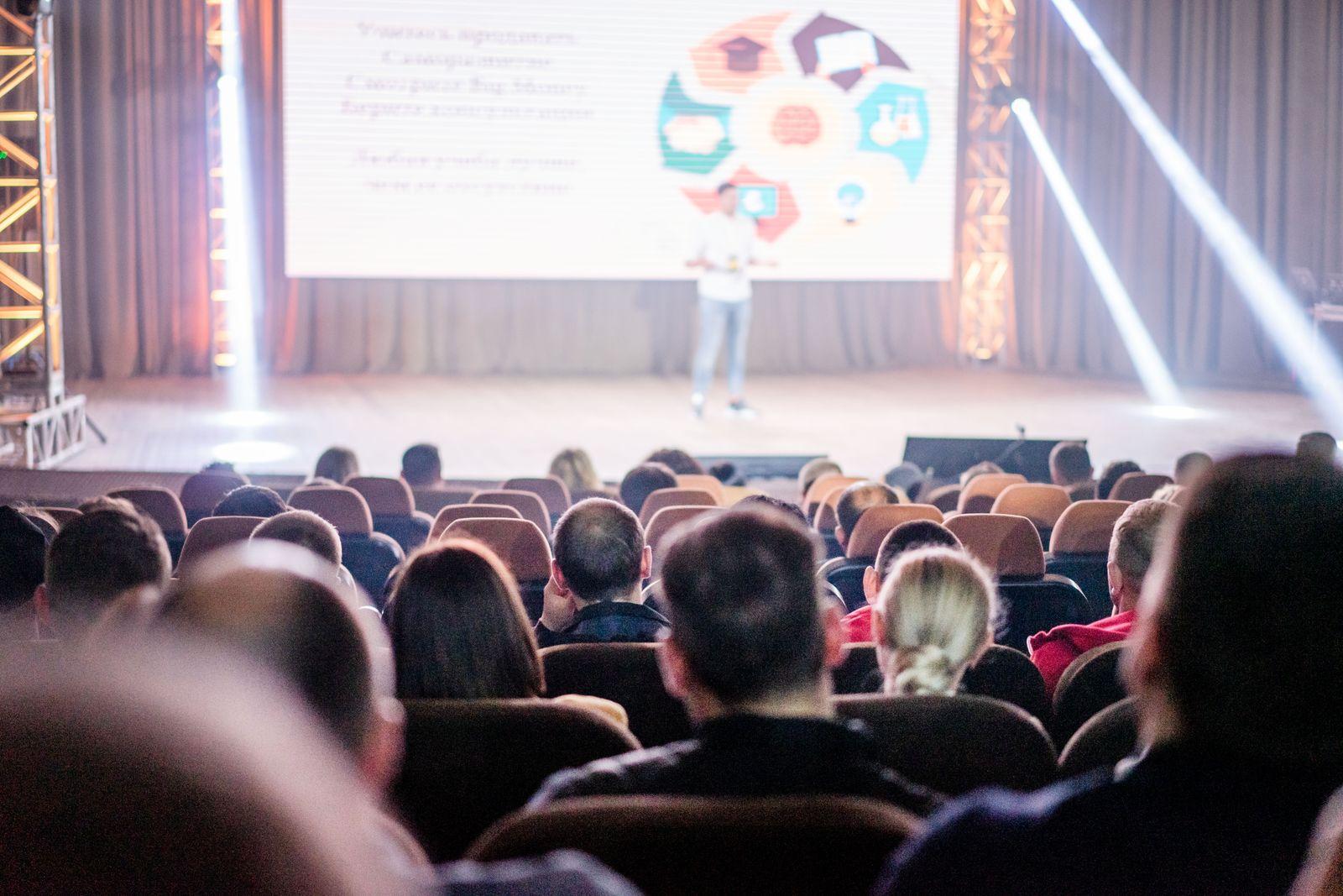 Conference audience watching a speaker's presentation in a large hall